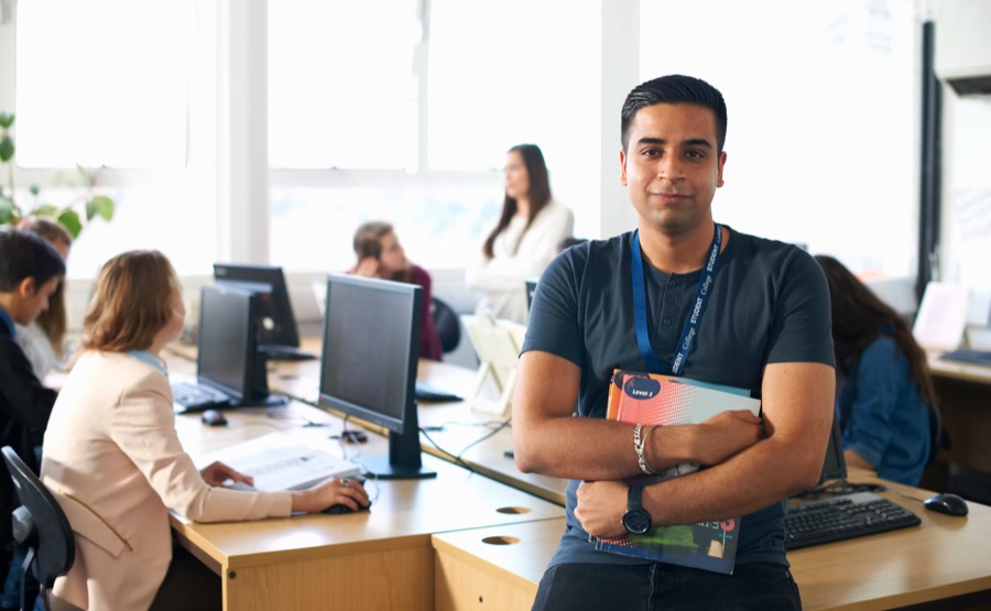 Male student holding course materials in a computer lab